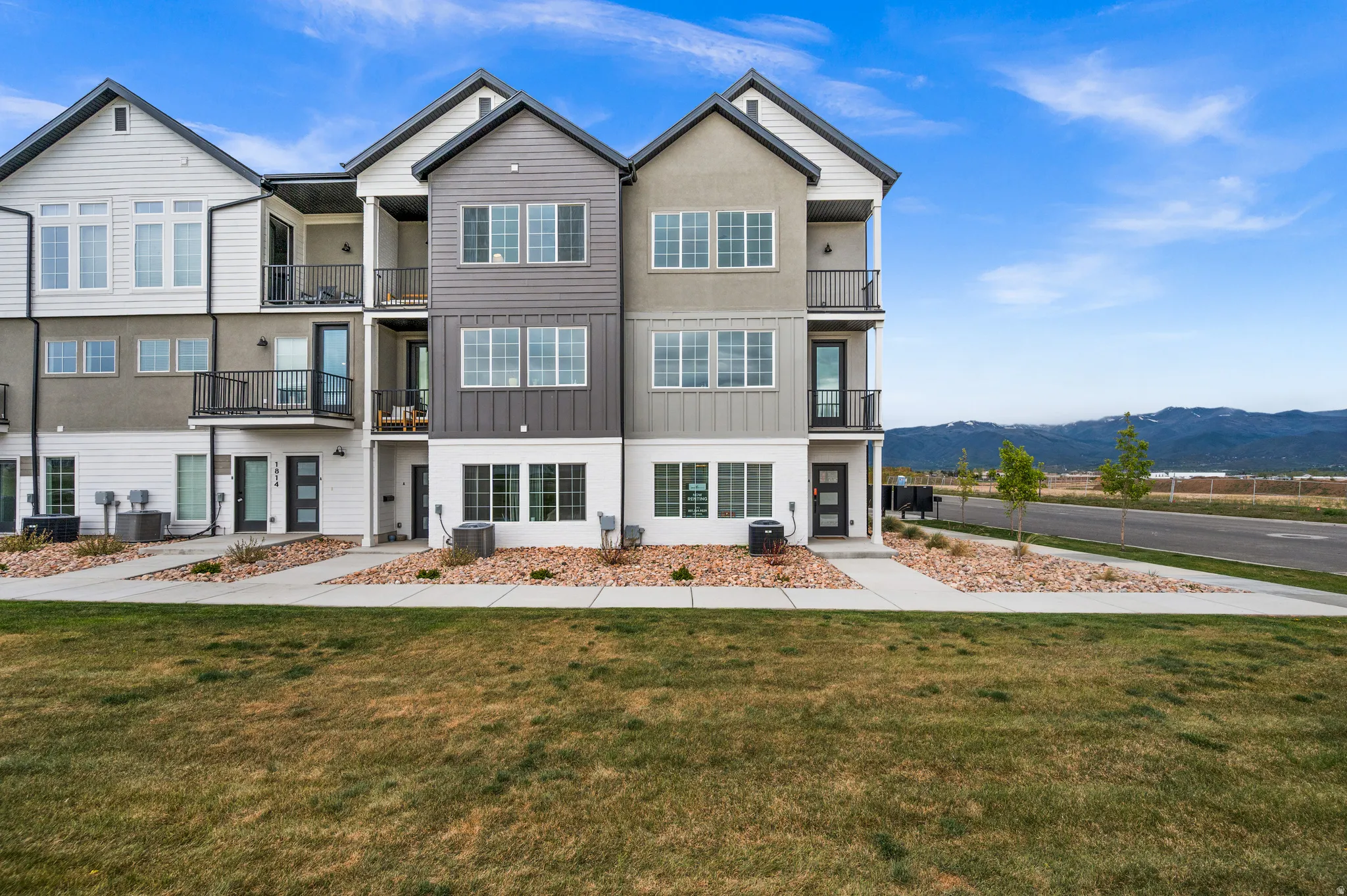 Contemporary townhome exterior featuring multi-toned siding, gabled rooflines, and multiple private balconies with black railings