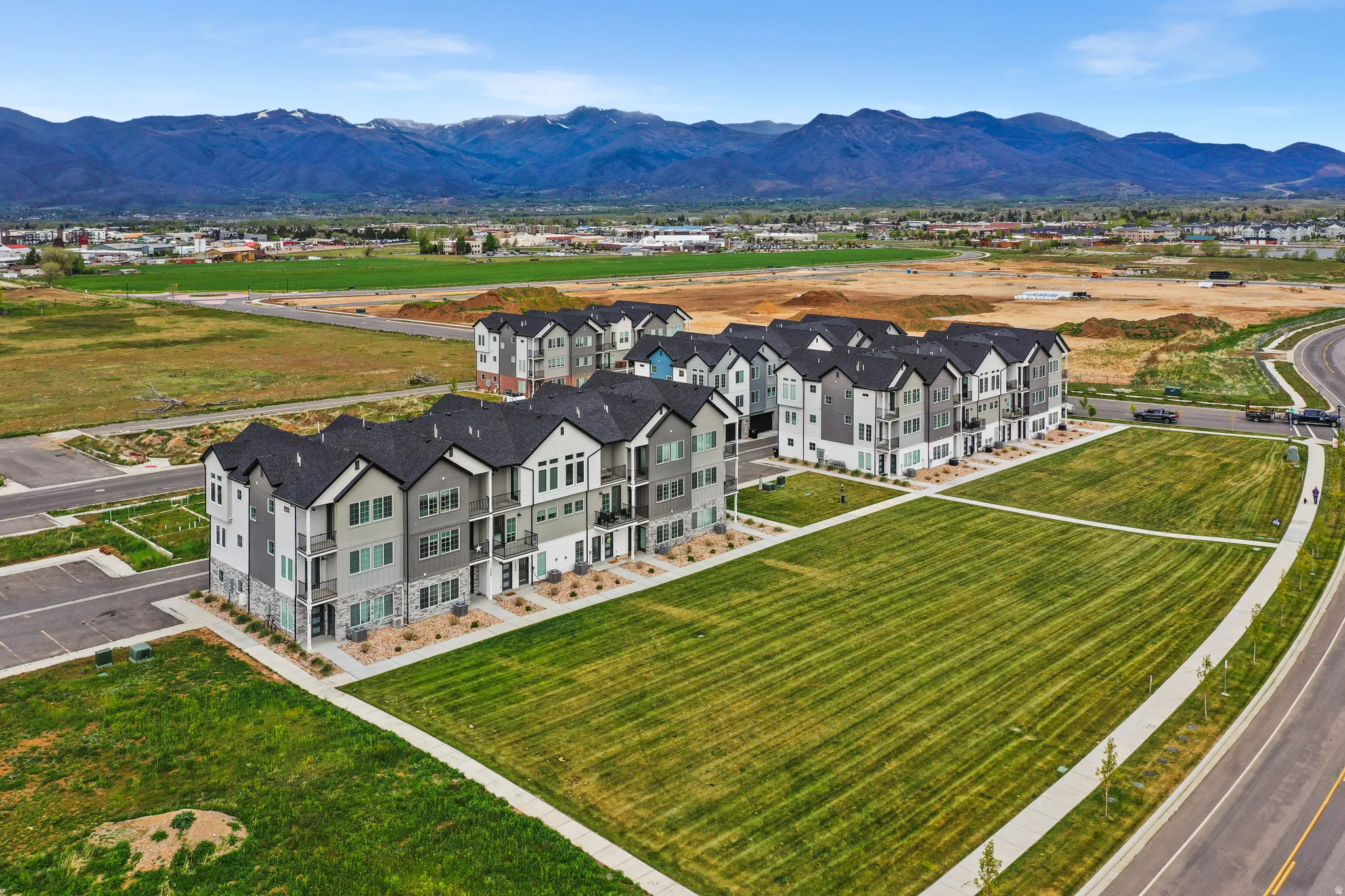 Modern multi-story residential buildings featuring contemporary architecture, dark shingle roofs, balconies, and a neutral color palette