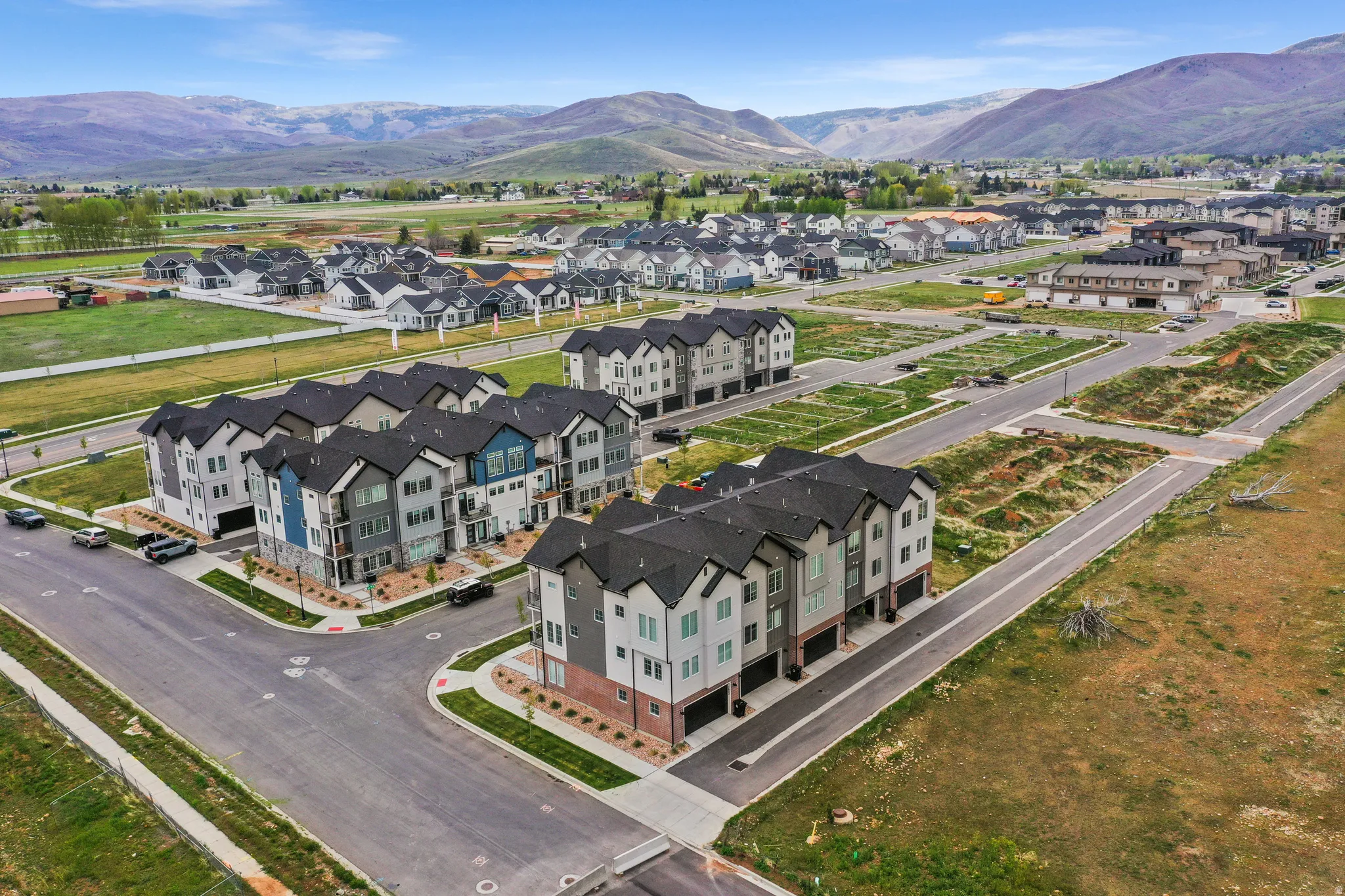 Modern townhome development featuring multi-story units, attached garages, and a mix of exterior siding materials including brick and paneling