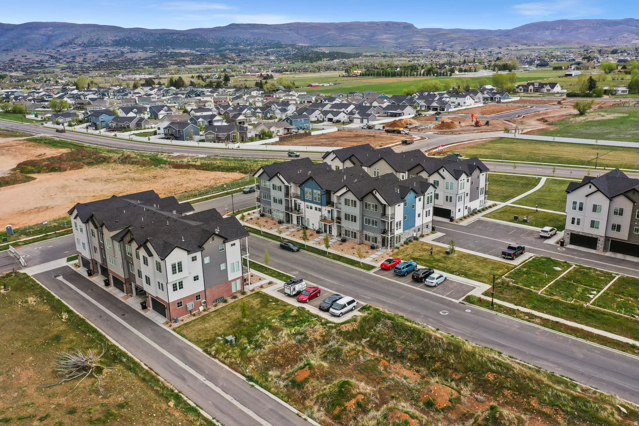 Modern multi-story residential buildings featuring varied exterior finishes, individual ground-level garages, and paved driveways