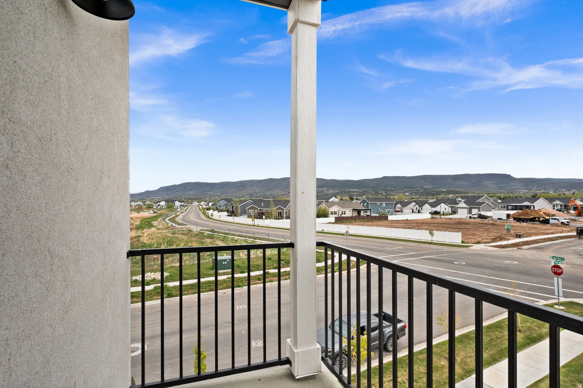Balcony featuring black metal railings and a white column, offering expansive territorial scenery with distant mountains