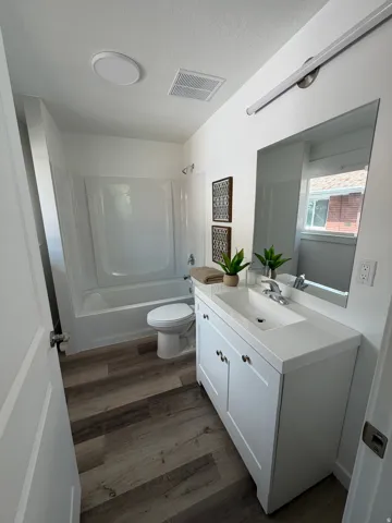 White vanity with shaker-style cabinetry, an integrated sink, and brushed nickel hardware