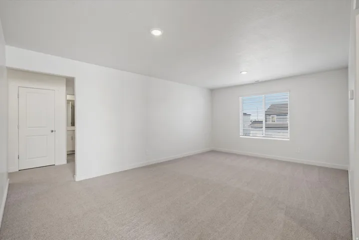 Spacious room featuring neutral carpeting, white walls, and recessed lighting