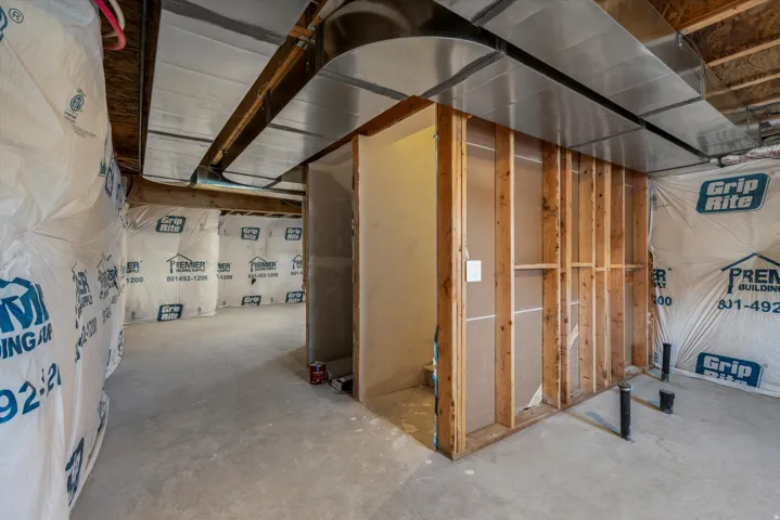 Unfinished basement space featuring exposed wooden joists, insulated exterior walls, and a concrete floor