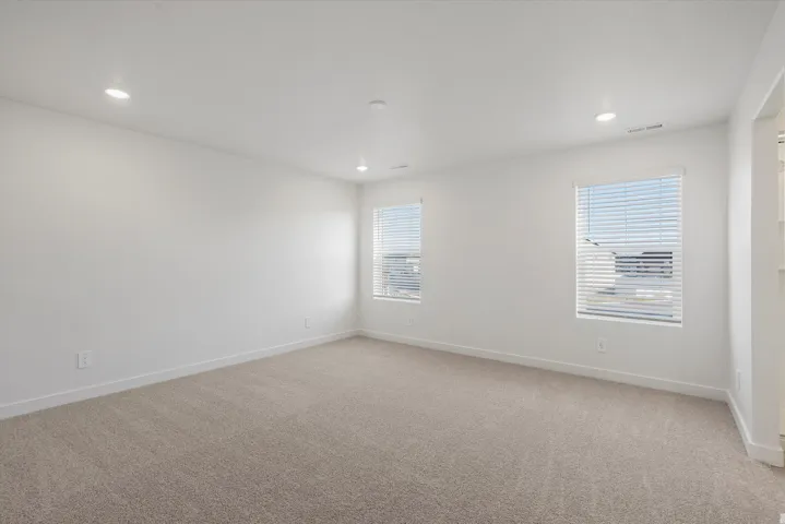 Spacious room featuring neutral carpet flooring and white walls