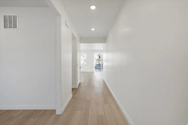Hallway featuring wood-finish flooring, recessed lighting, and white baseboards
