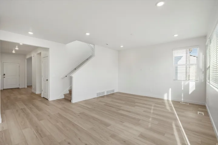 Open concept living area with light wood-finish flooring, recessed lighting, and white walls