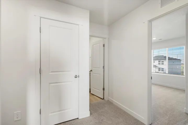 Hallway featuring white paneled doors, neutral carpeting, and white baseboards