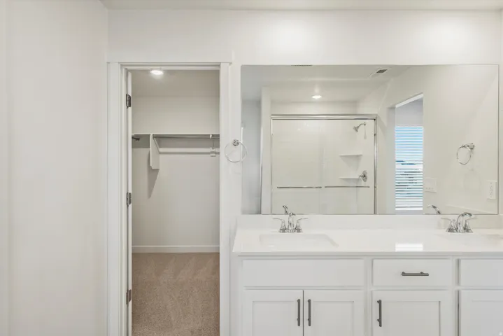 Double vanity with undermount sinks, chrome fixtures, and white cabinetry