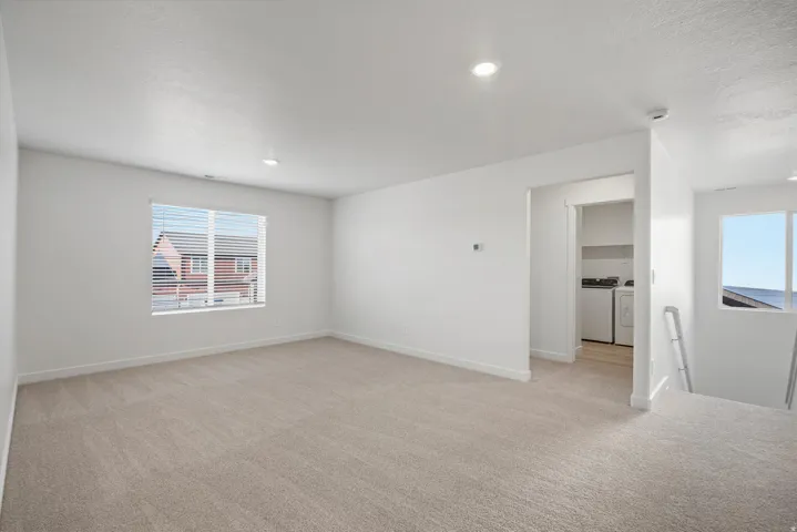 Upper-level living area featuring neutral carpeting and recessed lighting