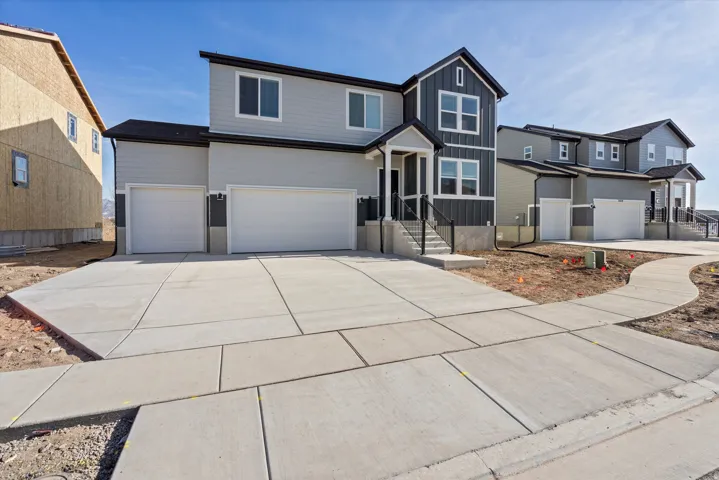 Modern multi-level exterior with a two-car garage, concrete driveway, and a welcoming front porch