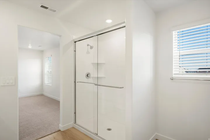 Walk-in shower with clear glass enclosure and subway tile surround