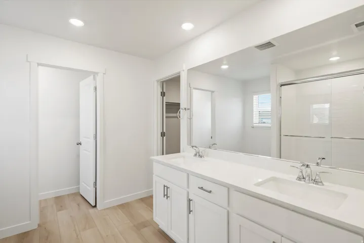 Dual vanity with white cabinetry, integrated sinks, and chrome fixtures