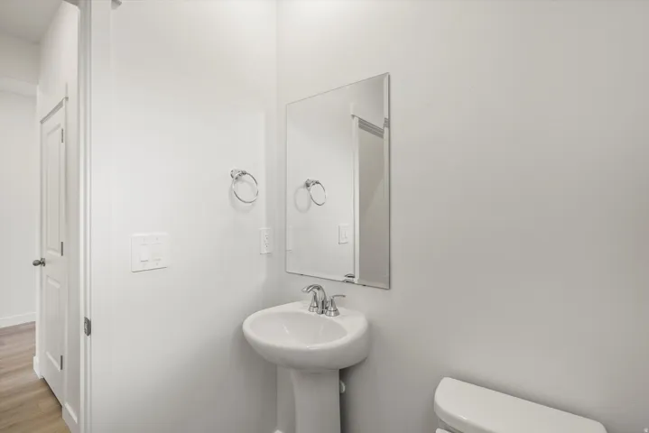 Pedestal sink with chrome faucet, framed mirror, and white walls