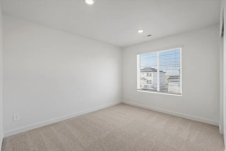 Carpeted room with recessed lighting, white walls, and a large window featuring horizontal blinds