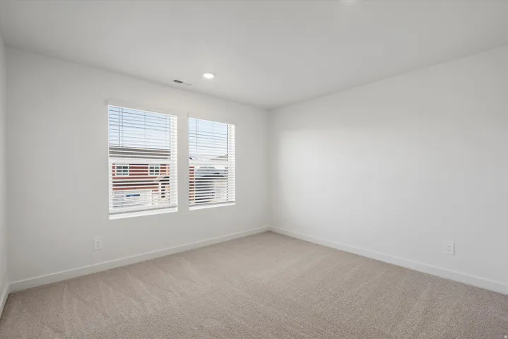 Bright room featuring two large windows with blinds, recessed lighting, and neutral carpeting