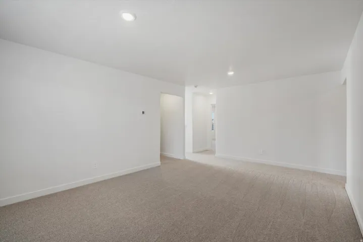 Spacious room featuring neutral carpet flooring, white painted walls, recessed lighting, and white baseboards
