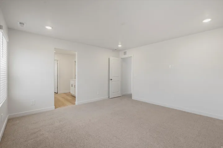 Spacious room featuring neutral carpet flooring, recessed lighting, and white baseboards