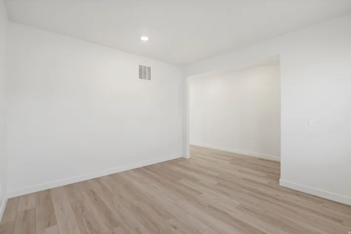 Spacious room featuring light wood-finish flooring, recessed ceiling lighting, and a wide entryway