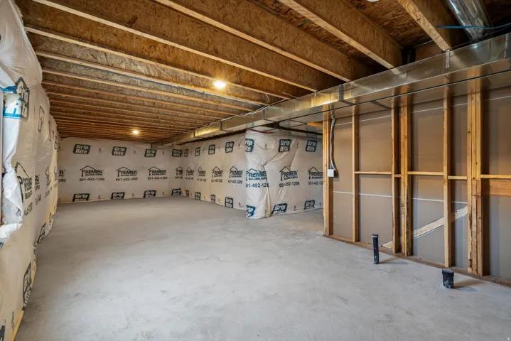 Unfinished basement featuring exposed wood joists, concrete flooring, framing for interior walls, and visible ductwork
