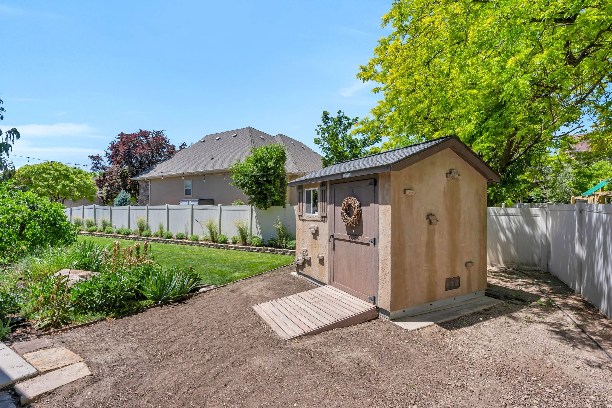 Backyard featuring a stucco-finish shed with a shingled roof, a wooden ramp, and a vinyl privacy fence