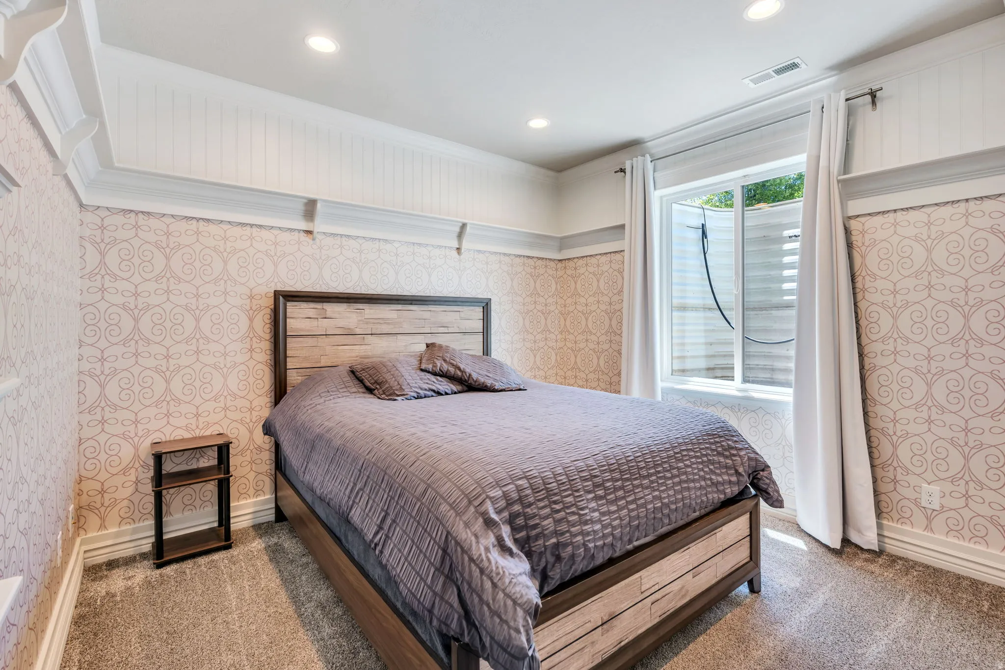 Carpeted room featuring patterned wallpaper and white wainscoting