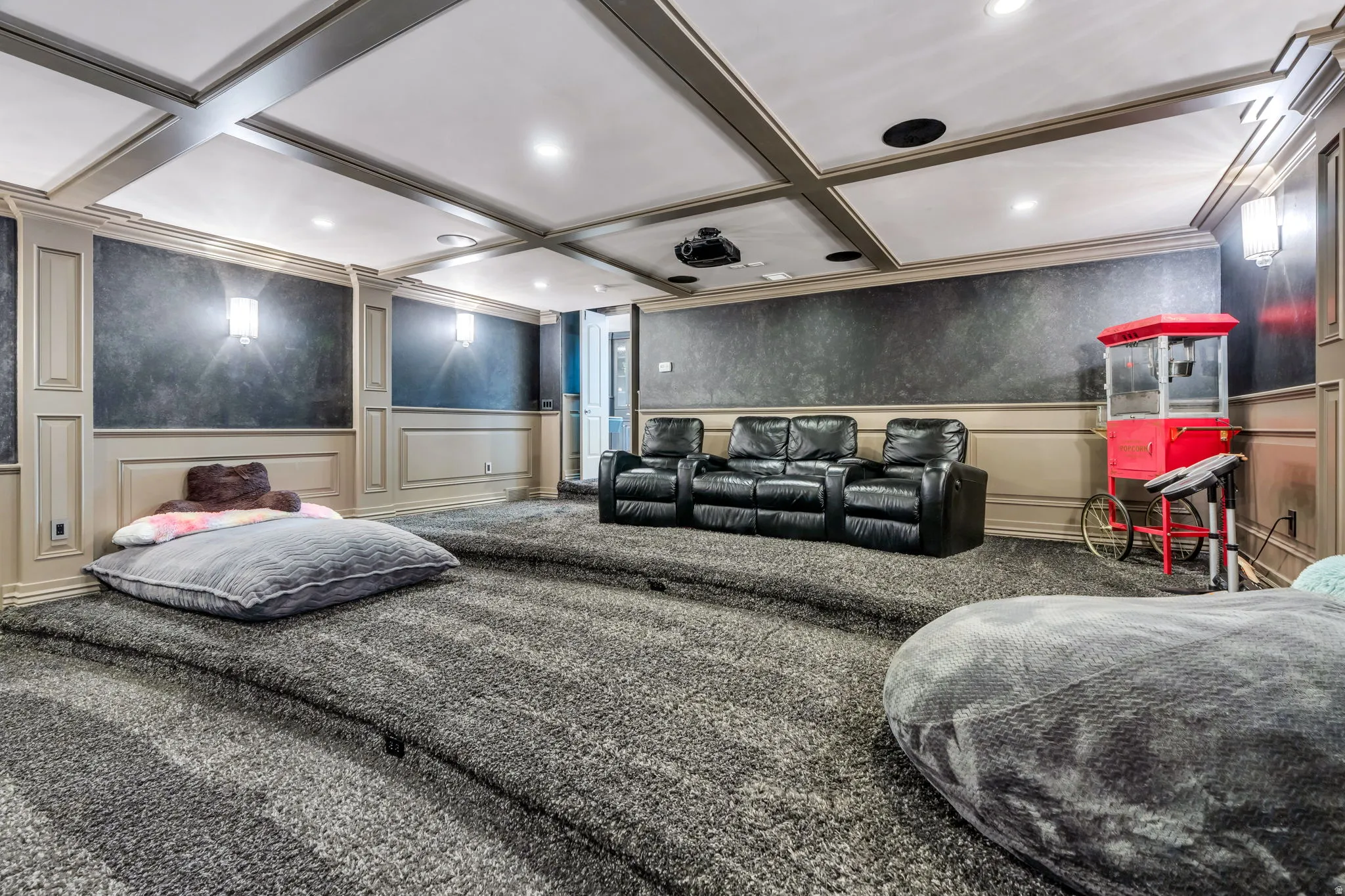 Dedicated media room featuring tiered, carpeted flooring and coffered ceilings with recessed lighting