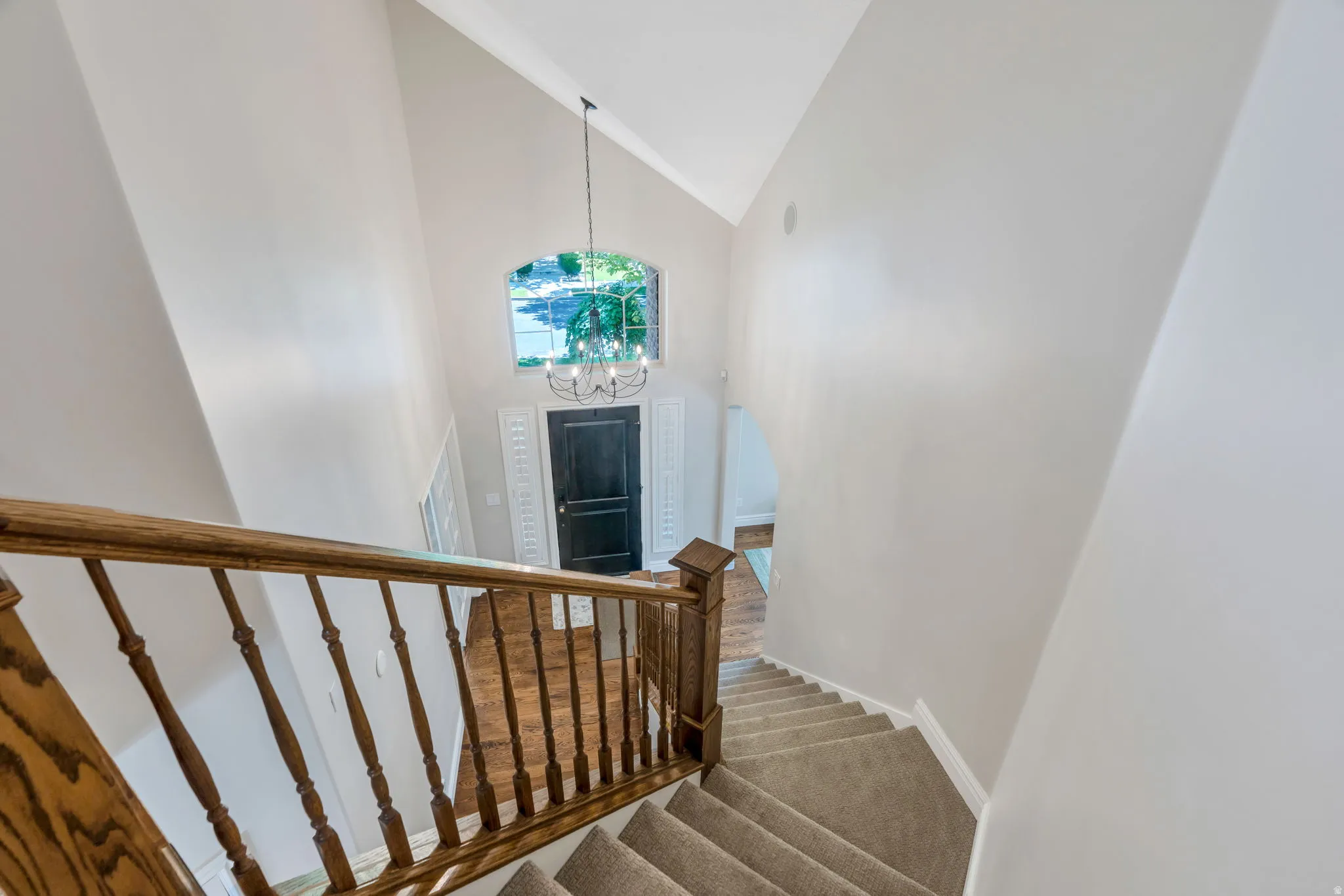 Two-story foyer with vaulted ceilings, a dark wood entry door, and an arched window