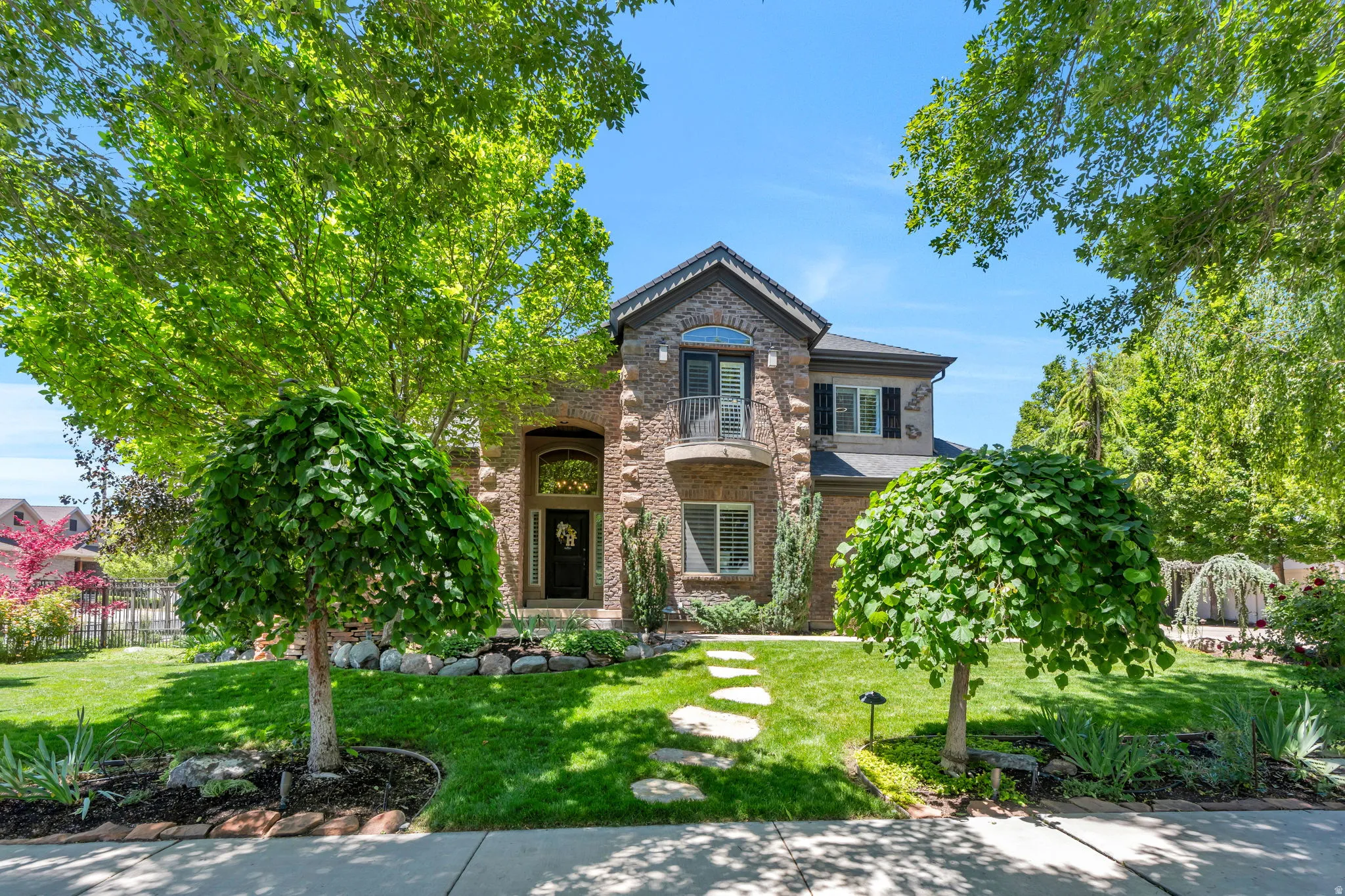 Two-story brick exterior featuring a front balcony and arched entryway