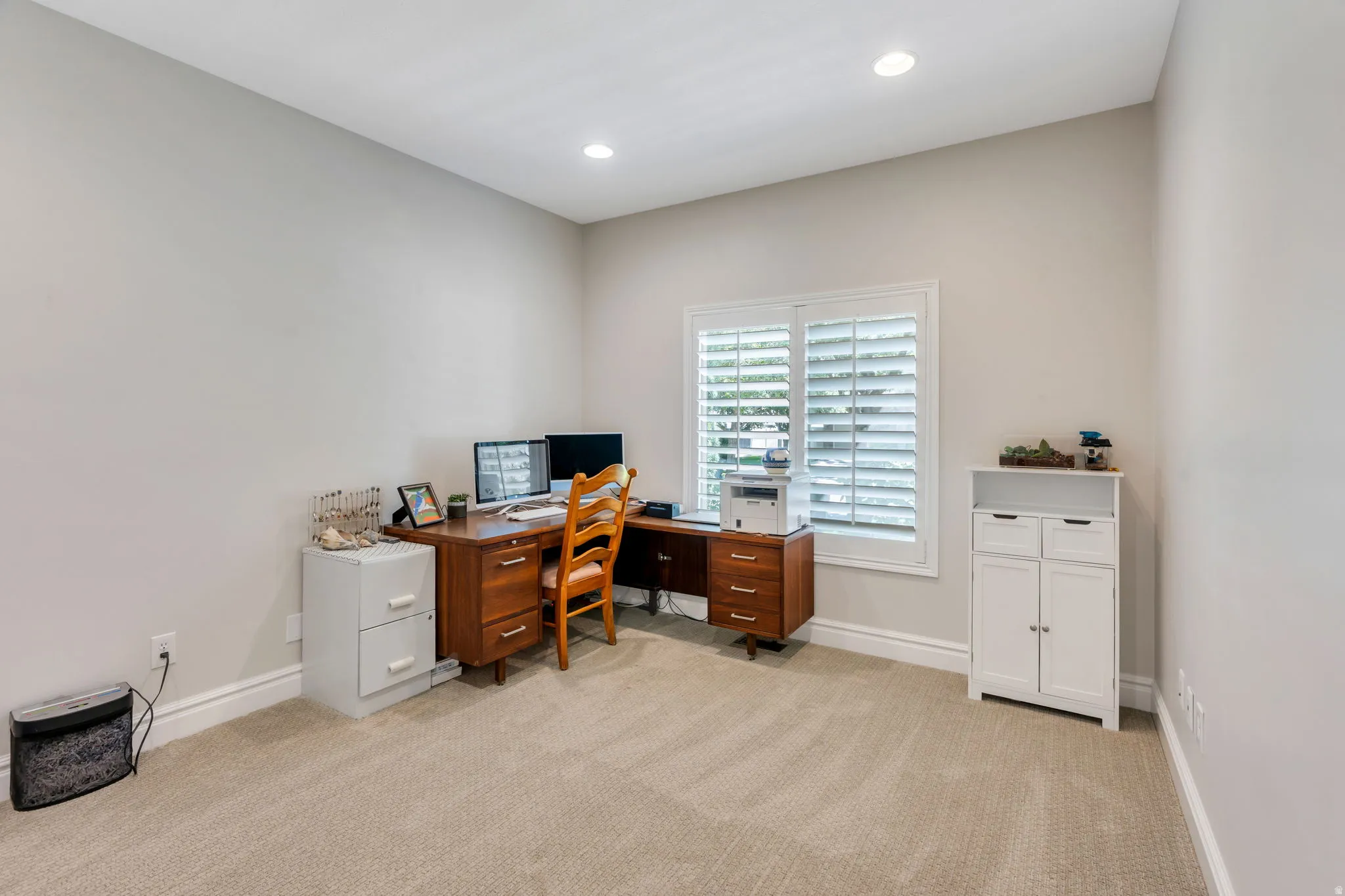 Carpeted room featuring recessed lighting, a window with plantation shutters, light-toned walls, and white baseboards