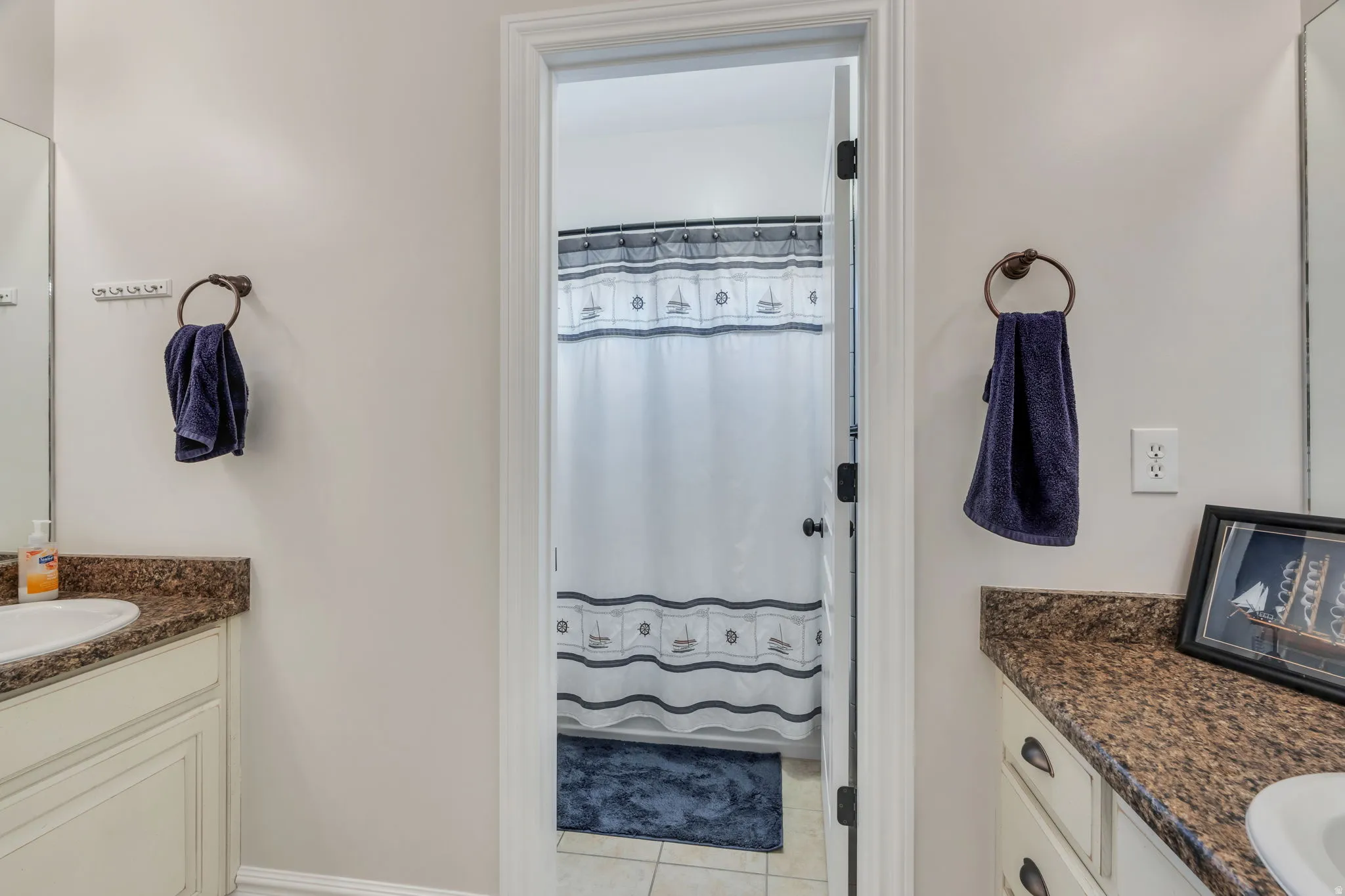 Bathroom featuring dual vanity areas with granite-style countertops and undermount sinks