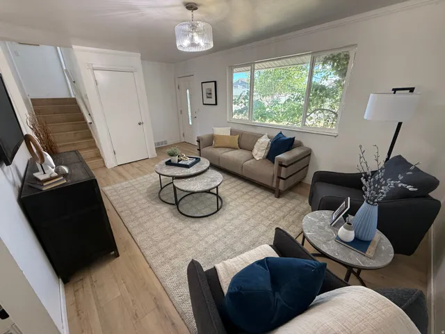 Living area featuring light wood-finish flooring, white walls, and a large multi-pane window