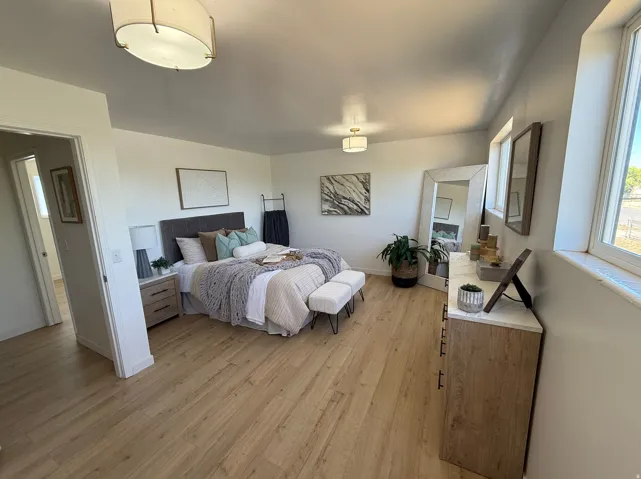 Spacious room featuring light wood-finish flooring, multiple windows, and a built-in recessed ceiling light fixture
