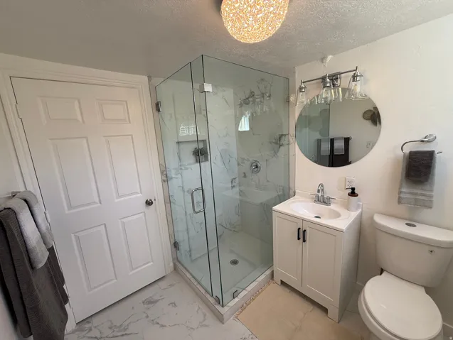 Glass-enclosed shower with a marble-patterned tile surround and built-in shower niche