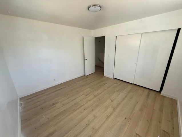 Room featuring light wood-finish flooring, white walls, and a flush-mount ceiling light