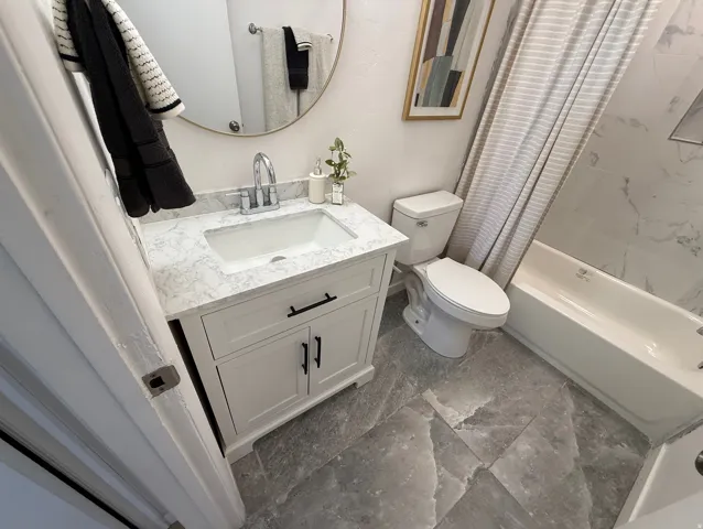 Bathroom featuring a white vanity with a stone-finish countertop, under-mount sink, and chrome faucet
