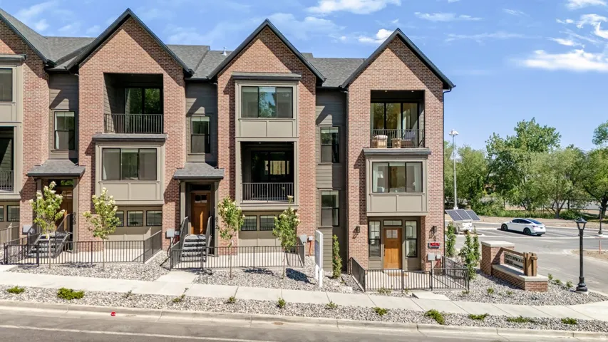 Contemporary multi-level townhome featuring a brick facade with dark gray siding accents
