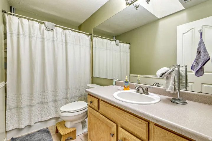 Bathroom featuring a vanity with a laminate countertop, integrated sink, and light wood cabinetry