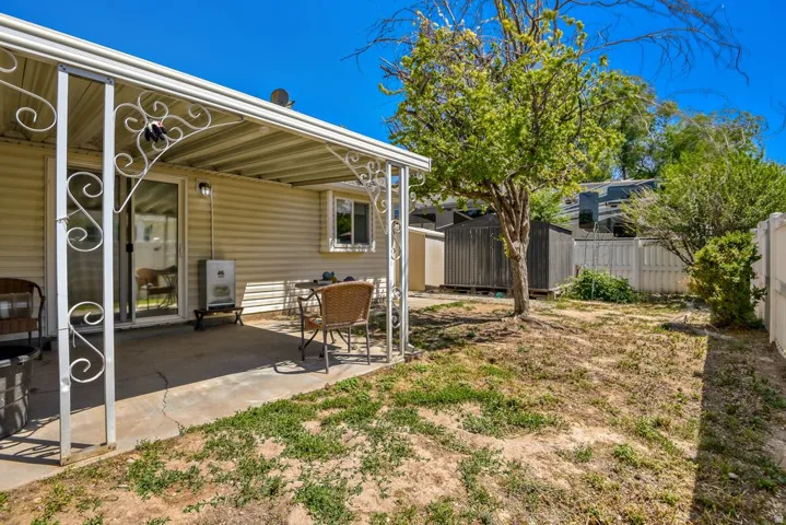 Rear patio with a white metal awning, sliding glass door access, vinyl siding, and a fenced perimeter