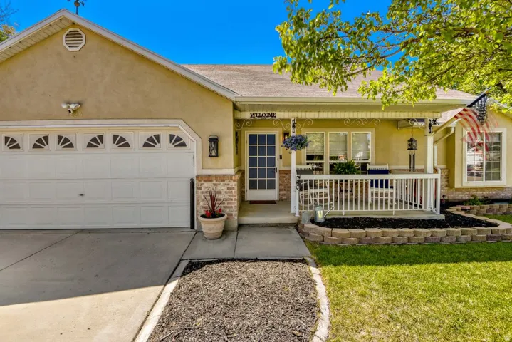 Front exterior featuring a covered porch with white railing, stucco siding, and stone veneer accents
