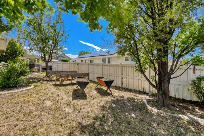 Expansive backyard featuring a mature tree, privacy fencing, and a covered patio area