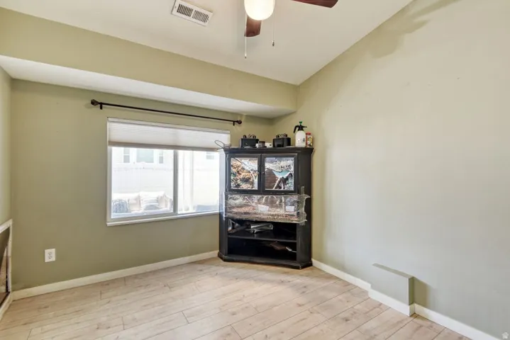 Room featuring light-toned wood-finish flooring and a single window with a roller shade