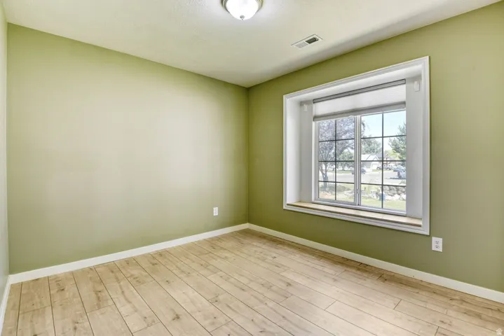 Room featuring a large window with white trim, a built-in window seat, wood-finish flooring, and light green walls