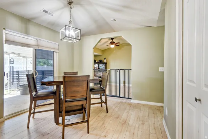 Dining area featuring wood-finish flooring, a contemporary ceiling light fixture, and a sliding glass door providing access to an outdoor patio