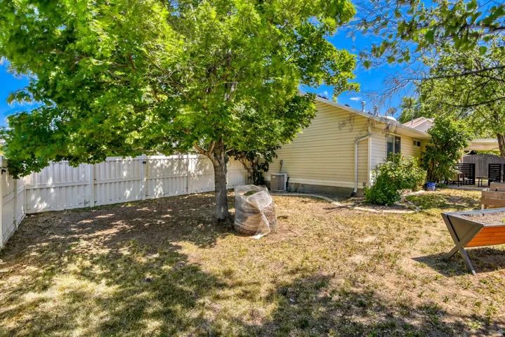 Private backyard featuring mature trees, a white perimeter fence, and ample space