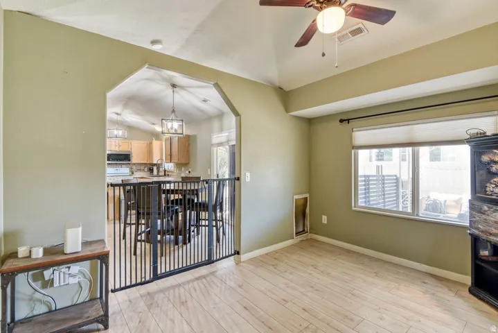 Open-concept living space featuring wood-finish flooring, a vaulted ceiling, and an arched entryway