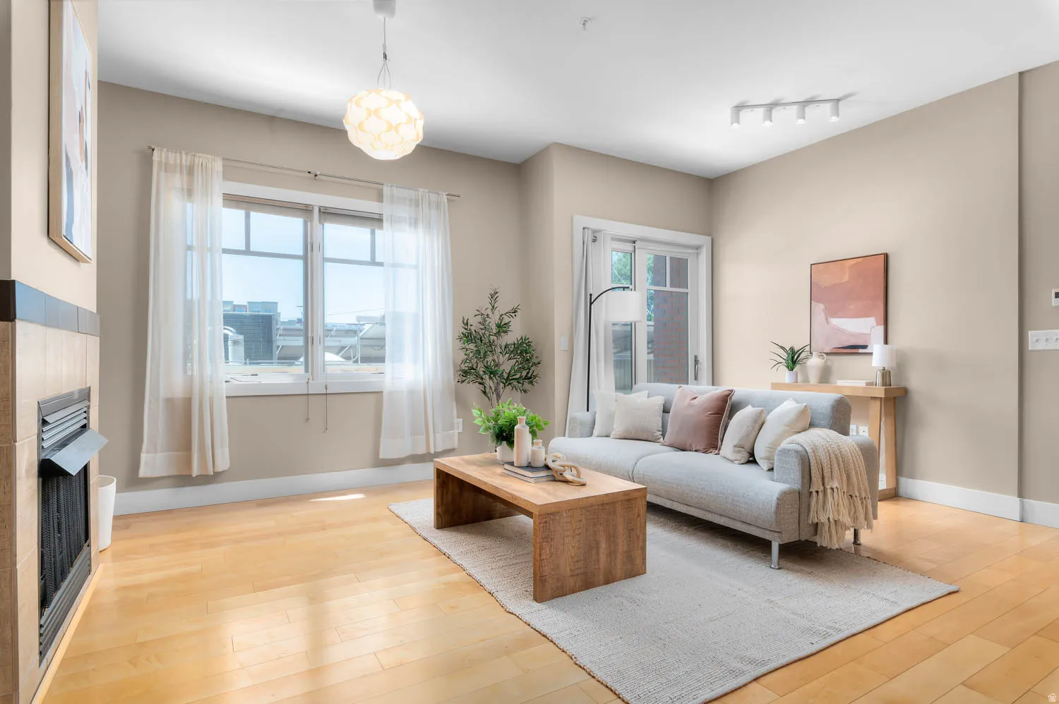 Living area featuring wood-finish flooring, a tiled fireplace, and a large window with transom details
