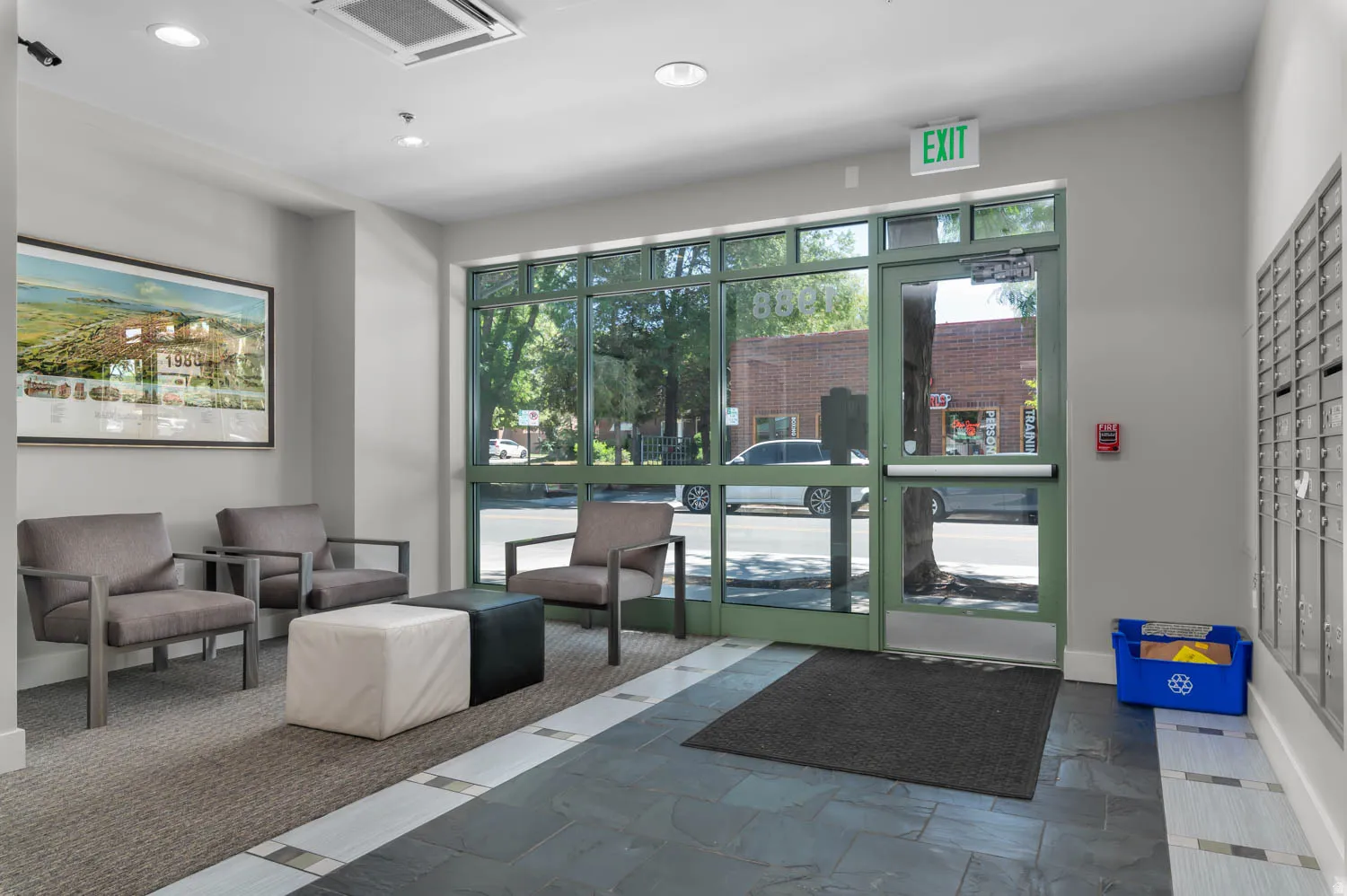 Lobby area featuring large storefront windows, recessed lighting, and a mailroom bank