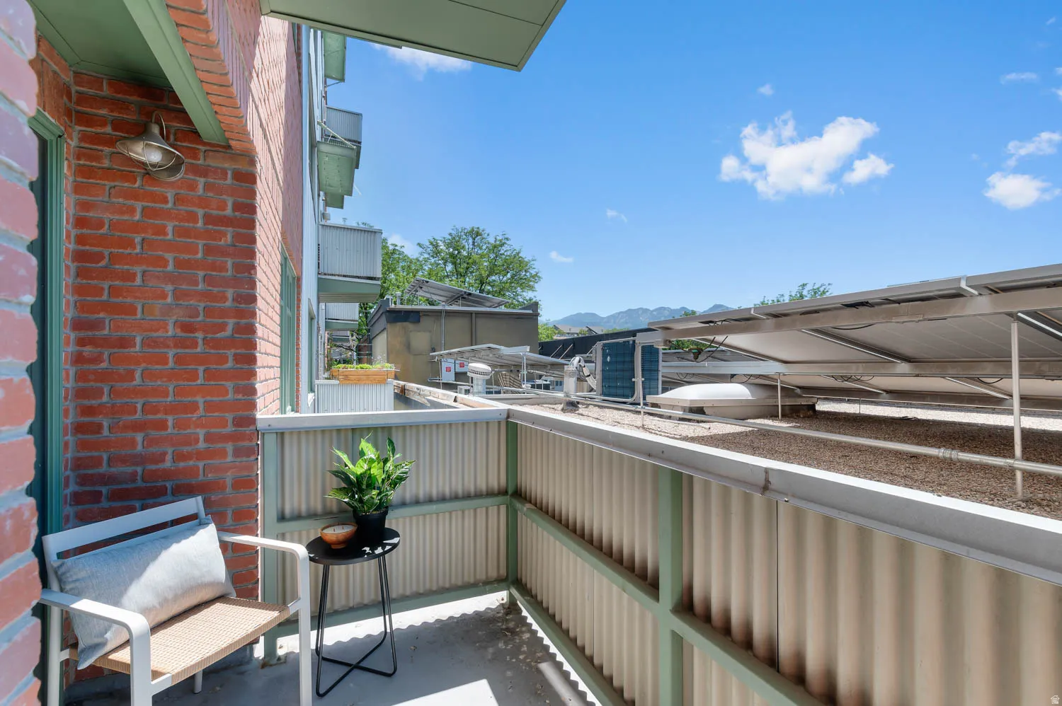 Private balcony with brick exterior and corrugated metal railing