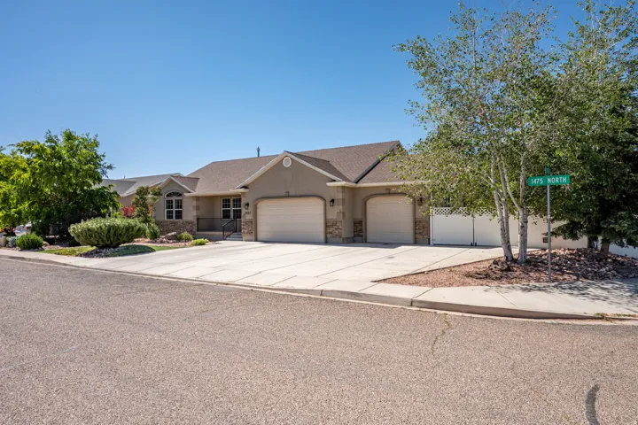 Stucco exterior with stone accents, featuring a two-car garage and an additional single-car garage